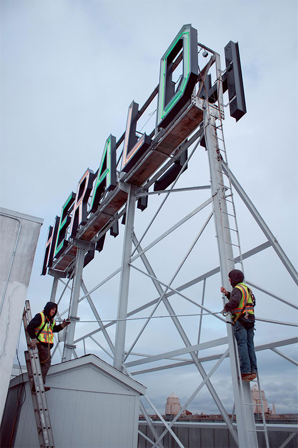 two workers servicing the herald rooftop sign