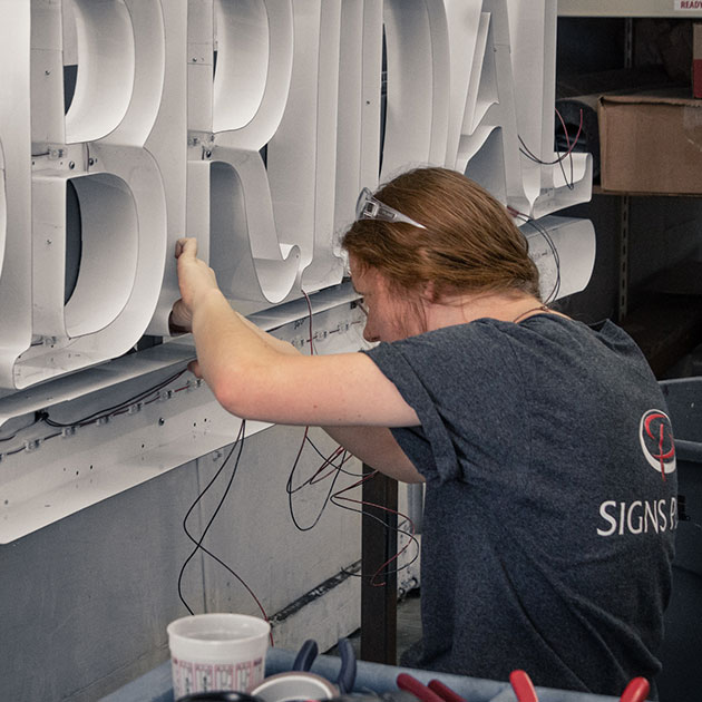 Mikayla Townsend populating channel letter sign with LEDs